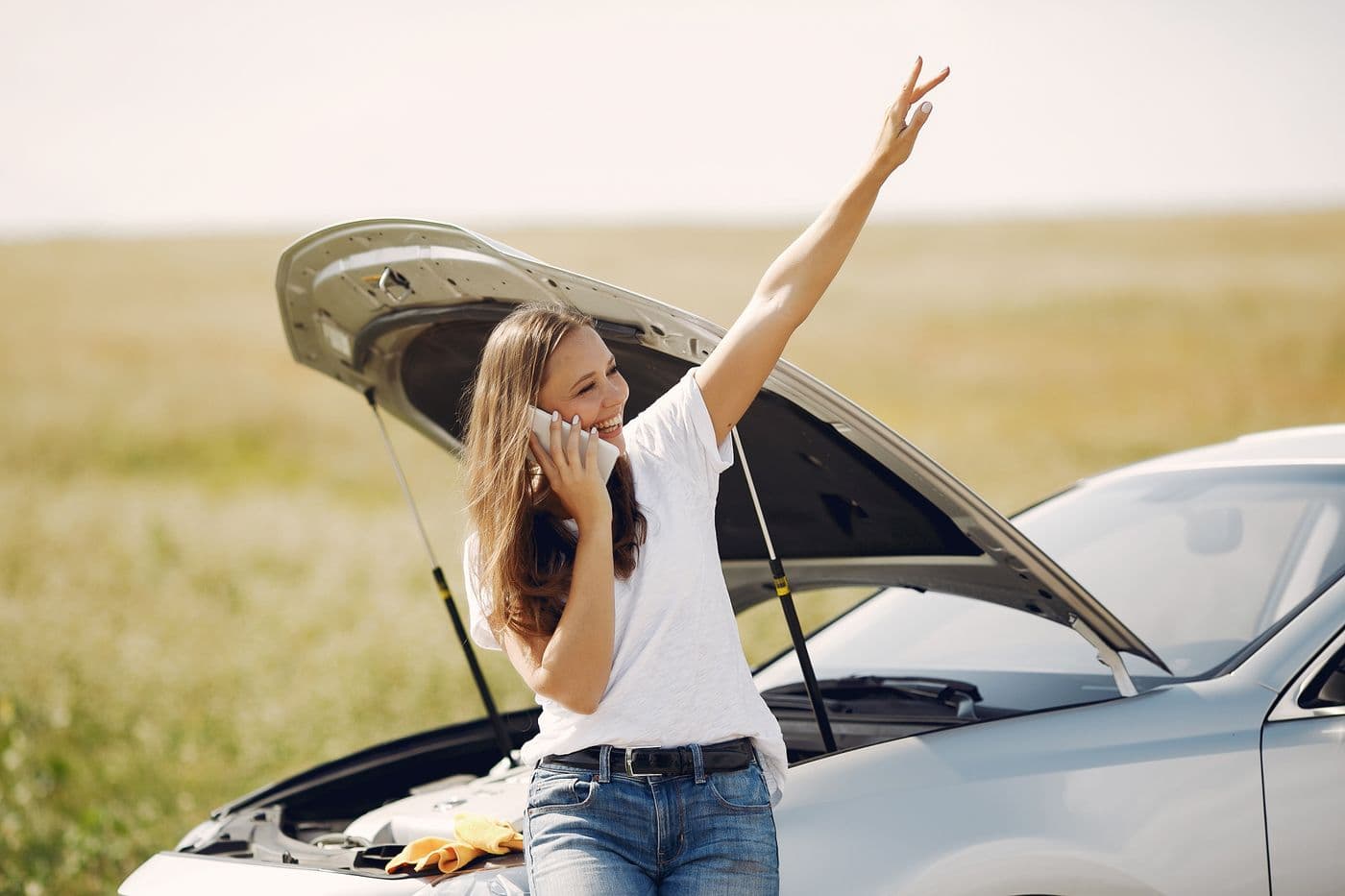Driver making a phone call beside her car with the hood raised