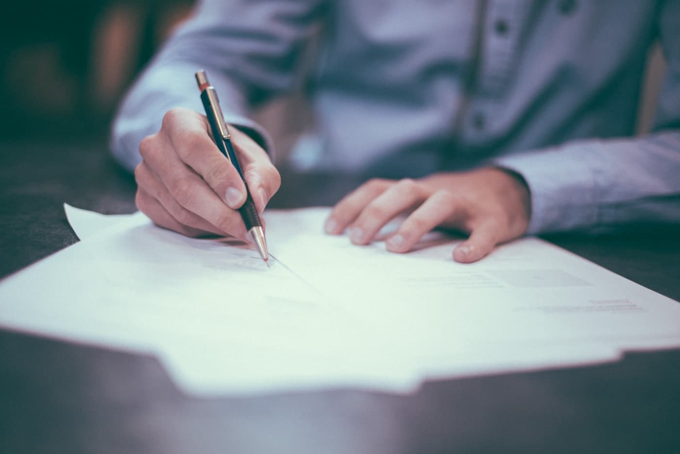Person completing report paperwork with a pen at a desk